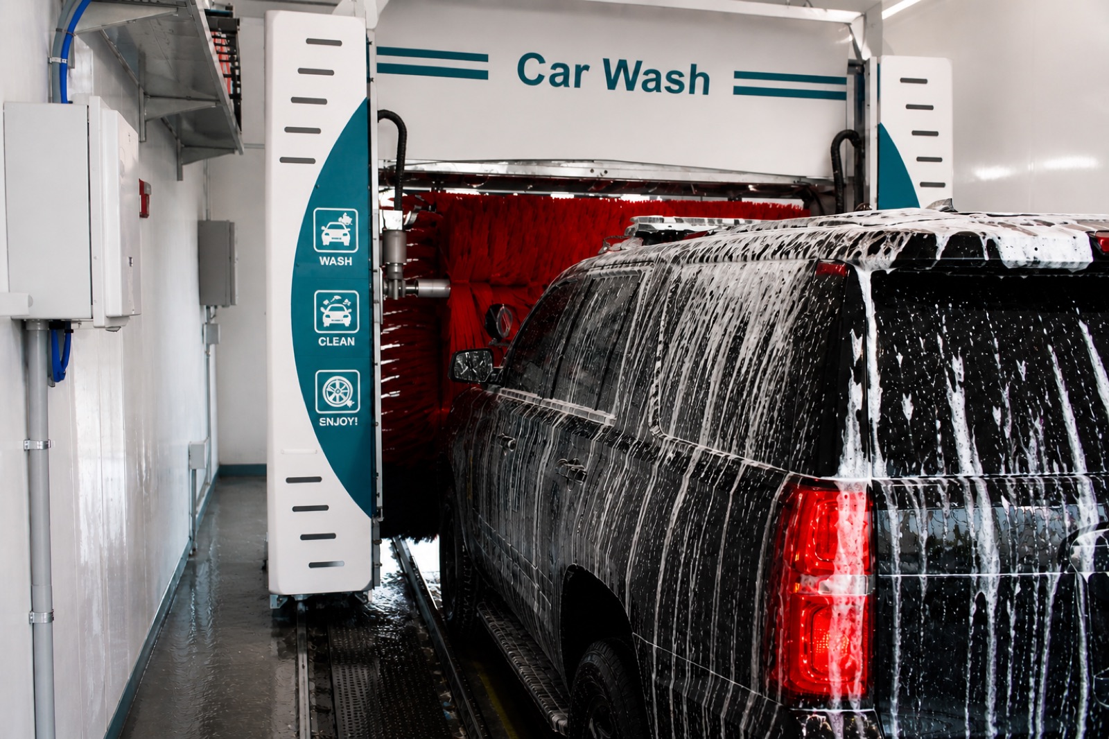 SUV inside Radio Road's express wash tunnel covered in foam, with branded wash arches overhead.